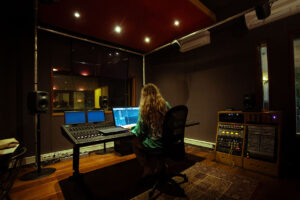 Audio engineer working at a mixing console surrounded by studio monitors and outboard gear at SAE Institute Amsterdam